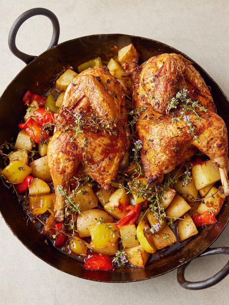 two chicken legs in a skillet with potatoes and herbs