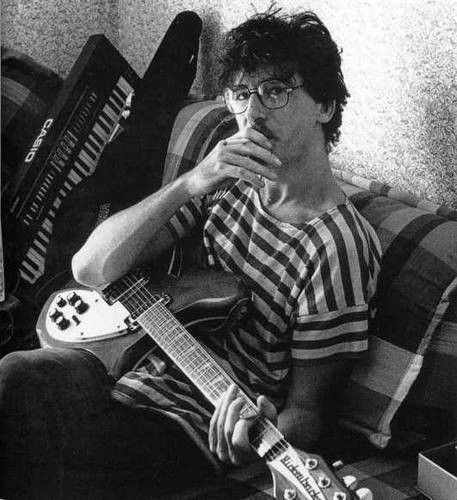 a man sitting on top of a couch holding an electric guitar in front of his face