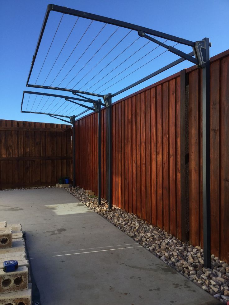 an outdoor area with a wooden fence and some rocks on the ground next to it