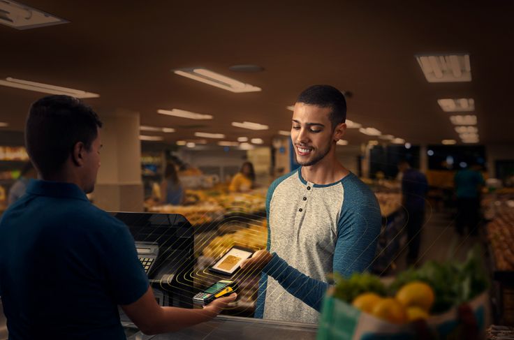 a man paying food from a cash register in a grocery store while another man looks on