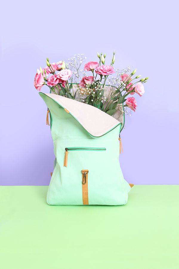 a green bag with flowers in it sitting on a purple and green table next to a blue wall