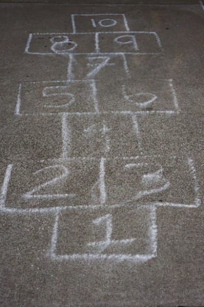 an area with chalk drawings on the ground and numbers written in white chalk next to it