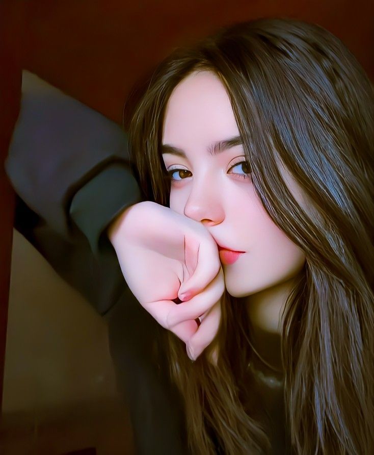 a woman with long brown hair is posing for the camera and has her hand on her face