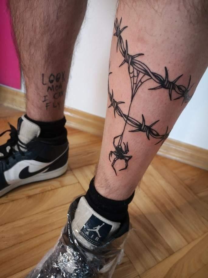 a man's leg with barbed wire on it and a spider crawling through the ankle