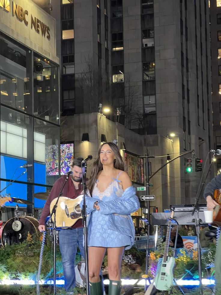 two people are singing and playing music in the city street at night, one person is holding a guitar