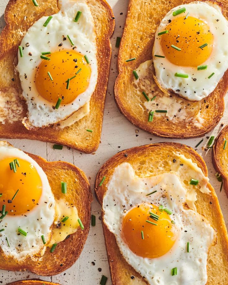 four pieces of toast topped with eggs and chives