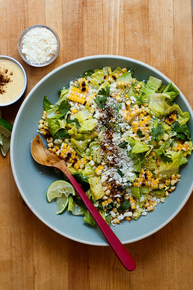 a salad with corn, lettuce and other toppings on a blue plate