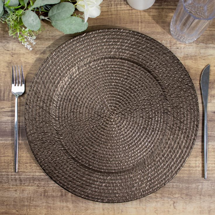 a place setting with silverware and flowers on a wooden table top in the background