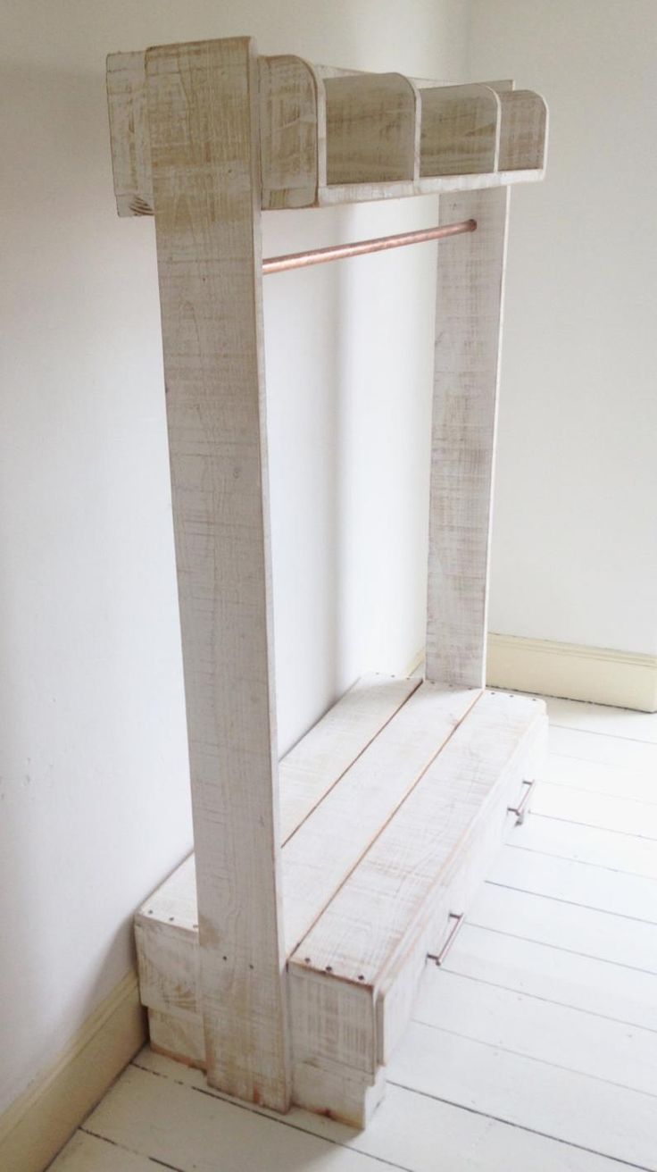 an empty room with white painted walls and wood flooring, including a bench made out of plywood planks