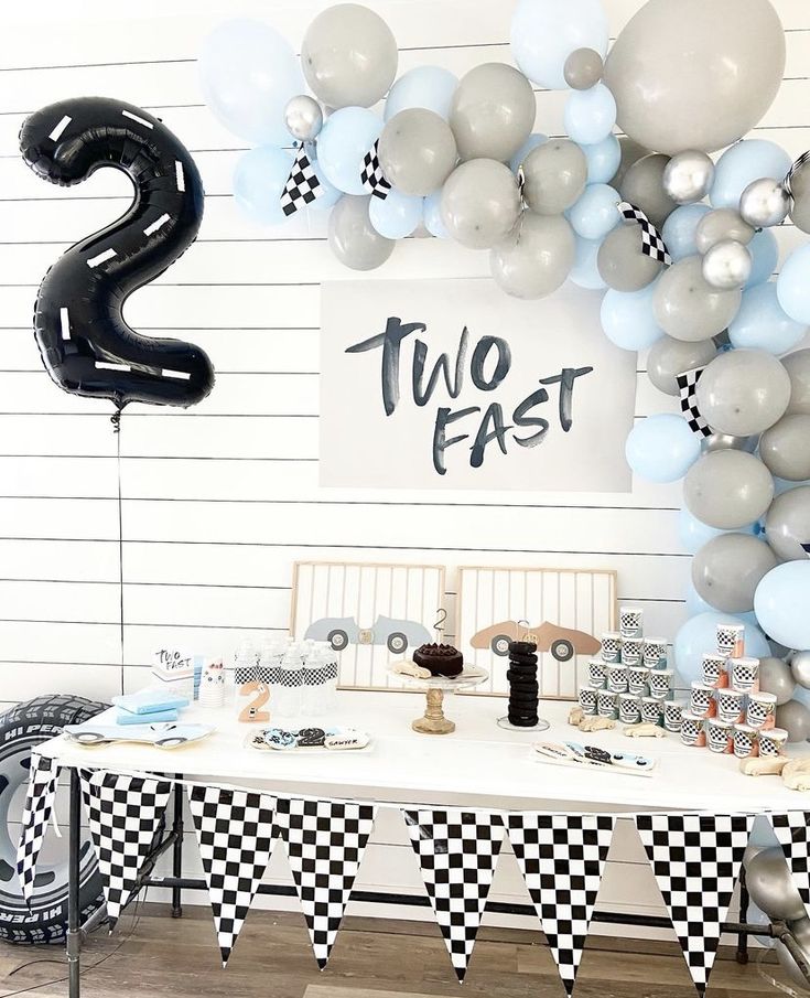 a table topped with balloons and cake next to a sign that says, two fast