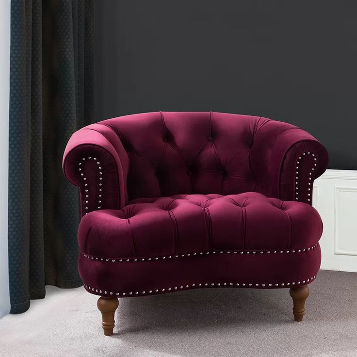 a red chair sitting in front of a window with black walls and curtains behind it