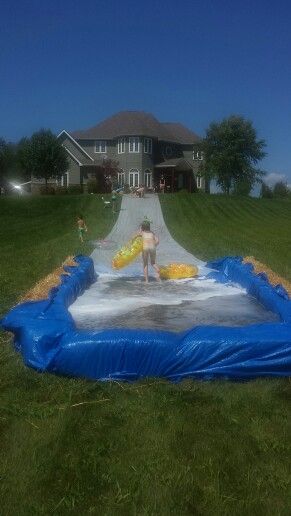 a large inflatable pool on the grass near a house with kids playing inside