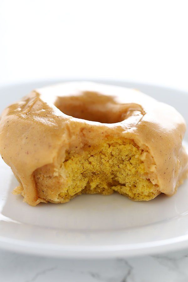 a glazed doughnut sitting on top of a white plate with a bite taken out of it