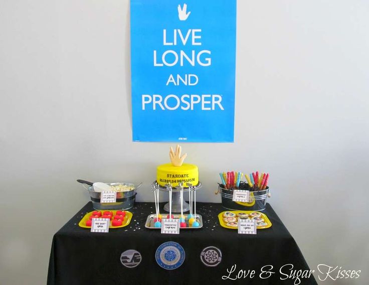 a table topped with cakes and desserts next to a sign that says live long and prosper