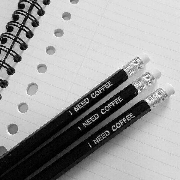 three black and white pencils sitting on top of a notepad next to each other