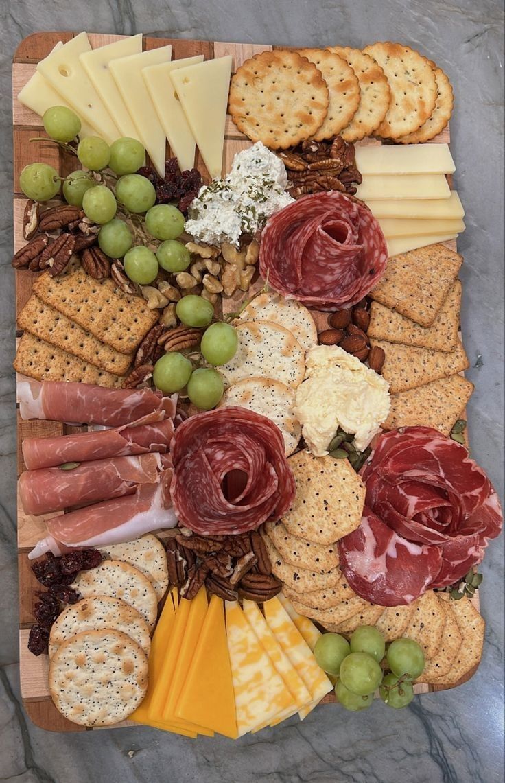 an assortment of cheeses, crackers and meats on a wooden platter