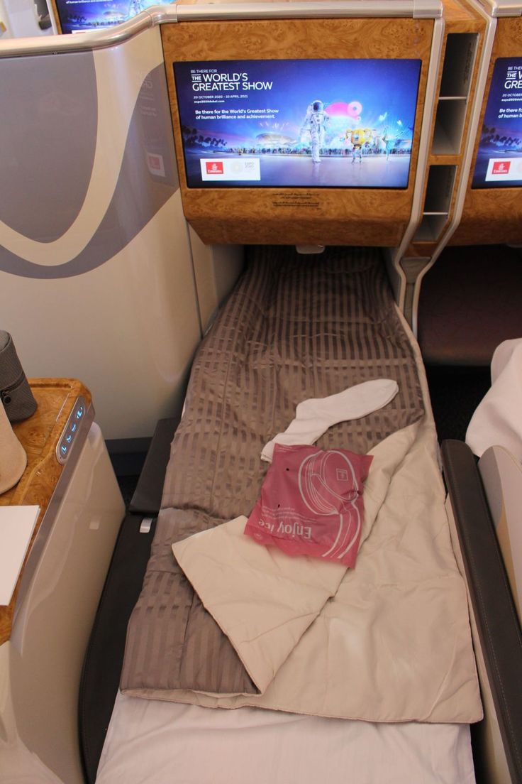 there is a small bed in the middle of an airplane with two televisions above it