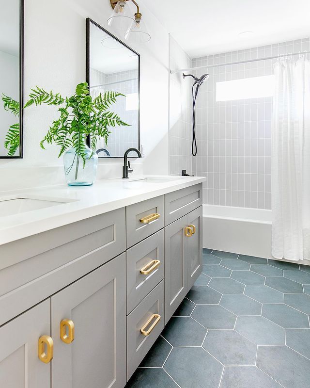 a bathroom with blue tile flooring and gold handles on the vanity, along with a large mirror over the sink