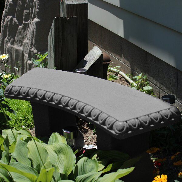 an outdoor bench sitting in the middle of some flowers and plants next to a house