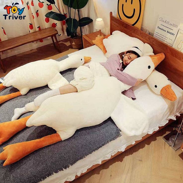 a woman laying on top of a bed covered in giant stuffed ducks next to a smiling child