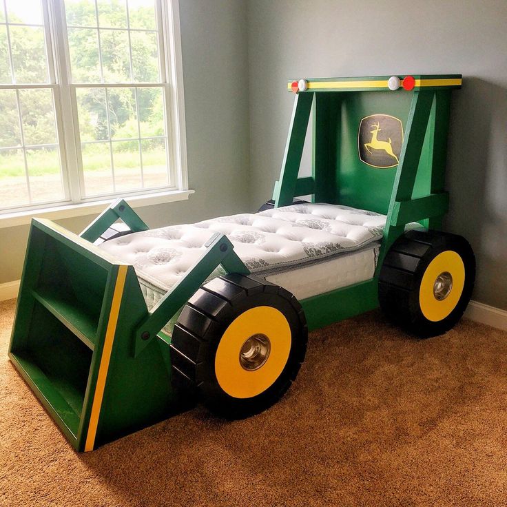 a bed made to look like a tractor with wheels on the bottom and sides, sitting in a bedroom