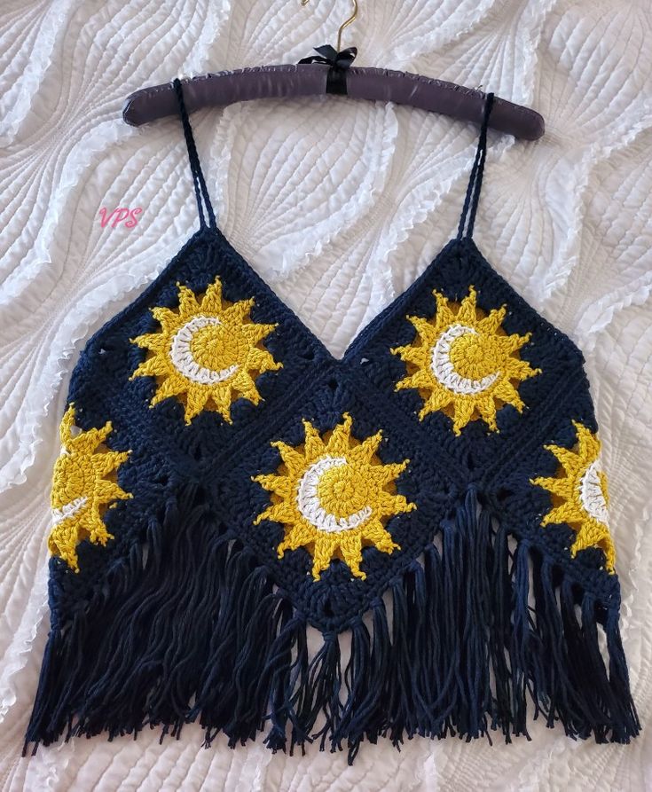 a crocheted sun and moon top hanging on a hook