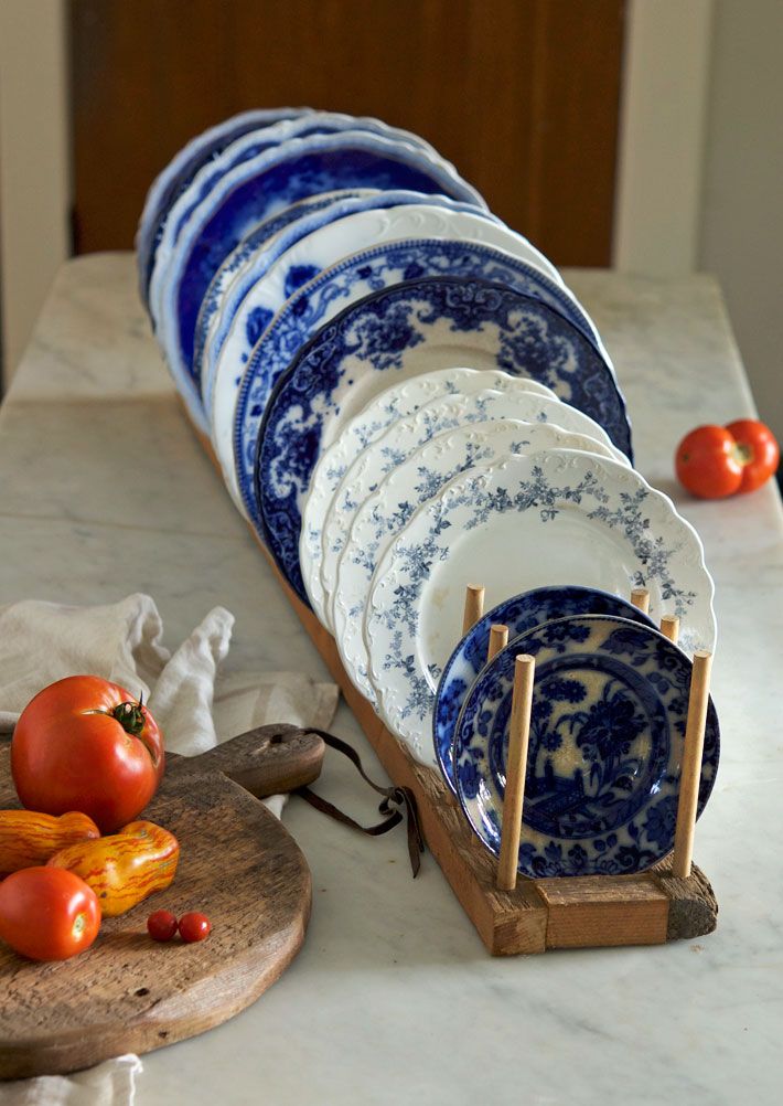 a stack of plates sitting on top of a wooden cutting board next to a pile of tomatoes