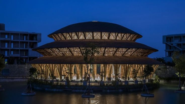 the building is lit up at night and reflecting in the water