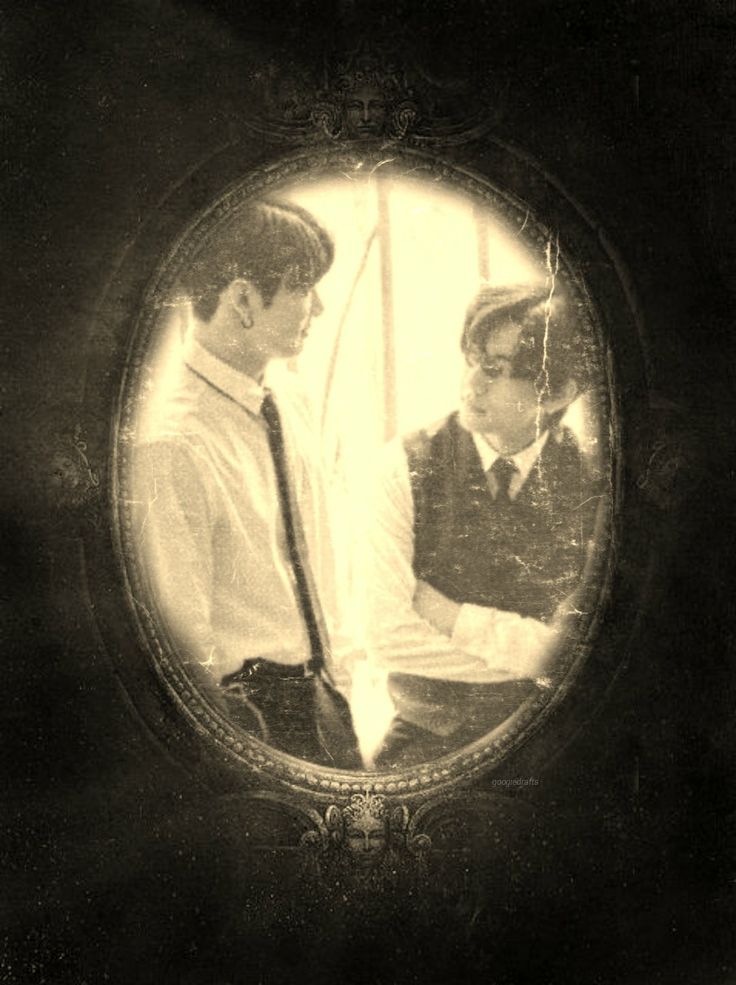 an old photo of two men in suits and ties looking at each other through a mirror