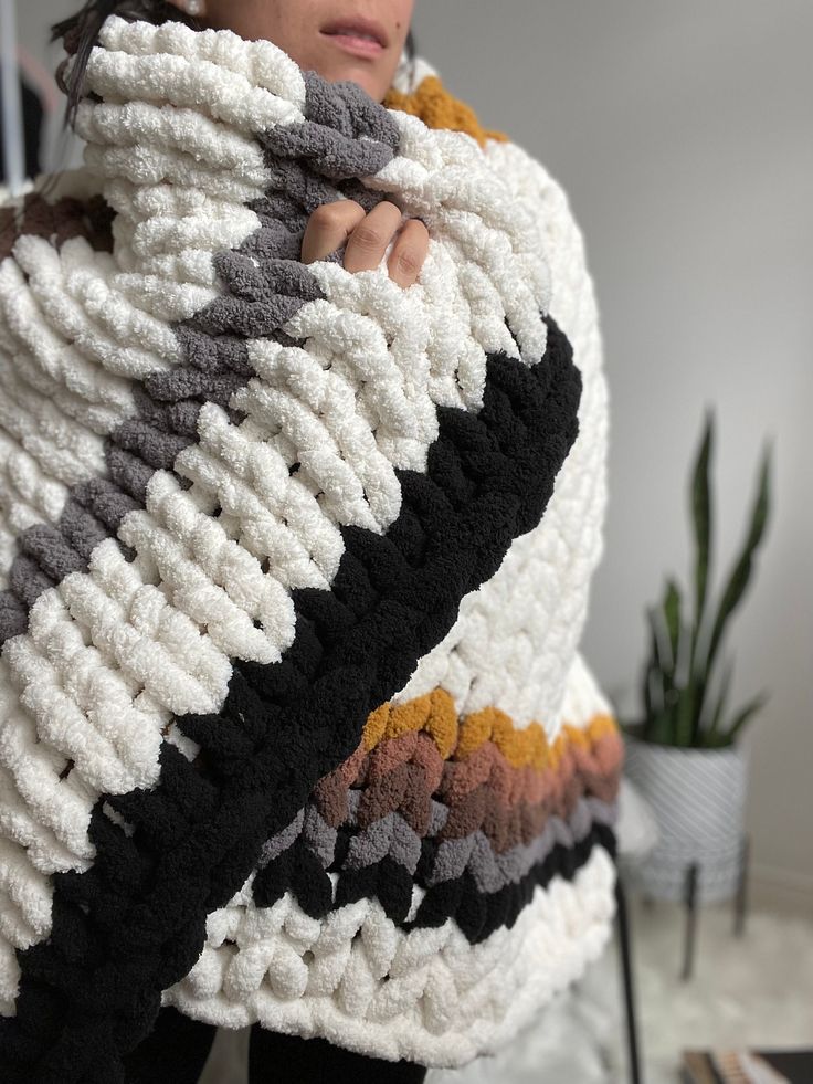 a woman is wrapped up in a crochet blanket