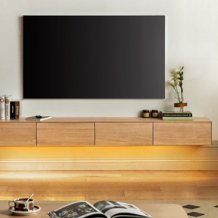 an open book is sitting on a table in front of a television that's mounted to the wall