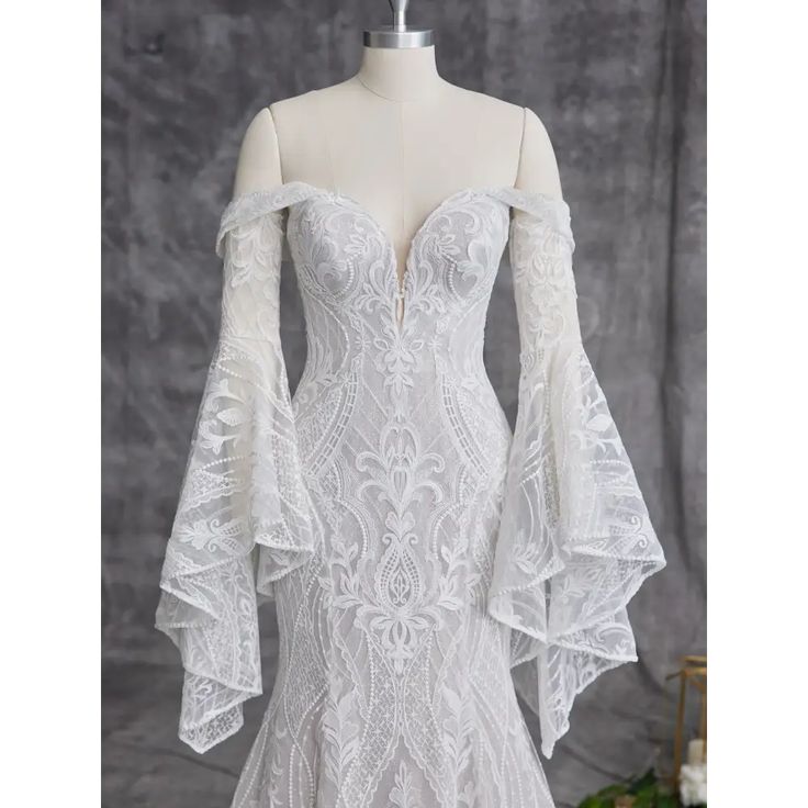 a white wedding dress with long sleeves and an off the shoulder lace pattern on it