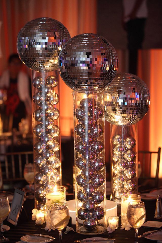 disco ball centerpieces with candles and place settings on a table at a party