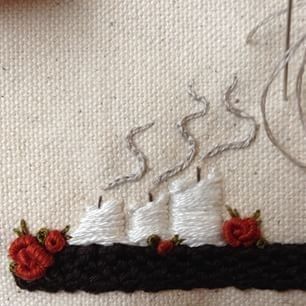 a close up of a piece of cloth with a boat on it and some thread