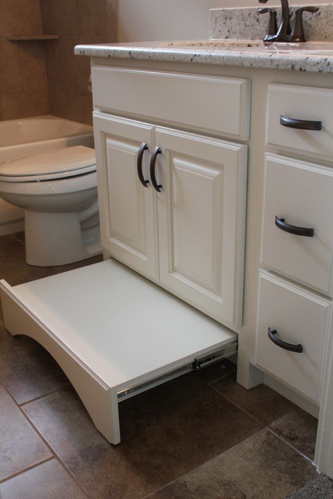 a white toilet sitting next to a sink under a bathroom vanity with an open drawer