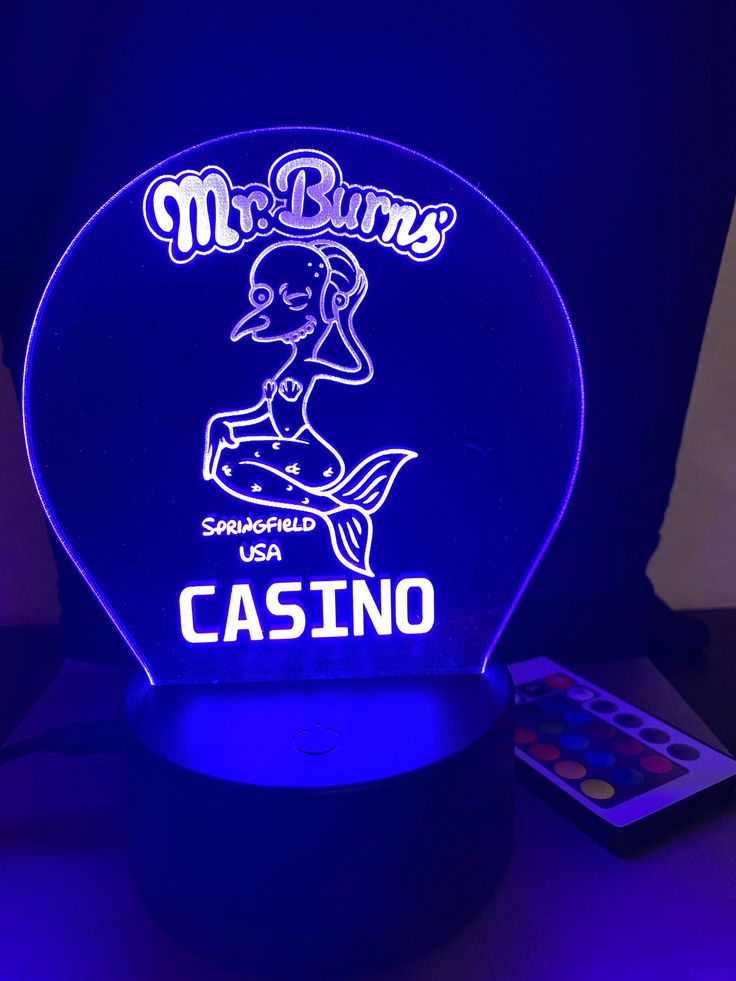 a blue light up lamp with the words mr burns casino on it and a remote control next to it