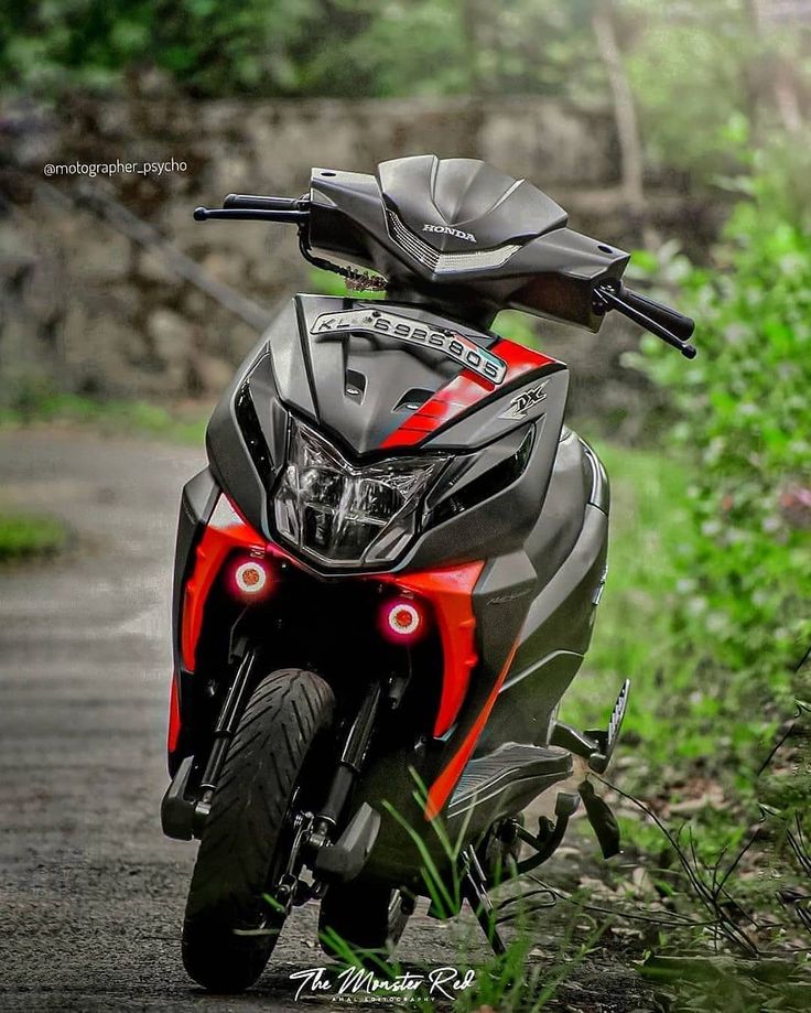 a red and black motorcycle parked on the side of a road next to some grass