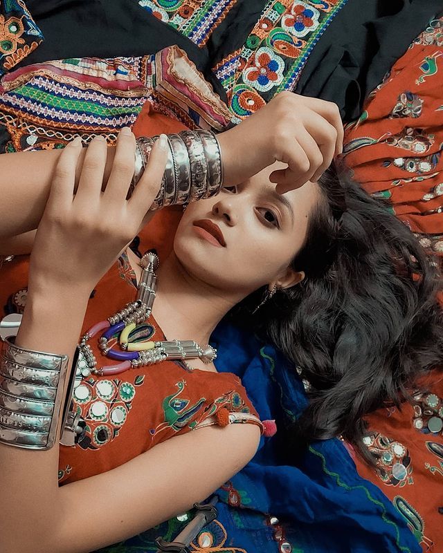 a woman laying on top of a bed covered in bracelets and rings with her hands