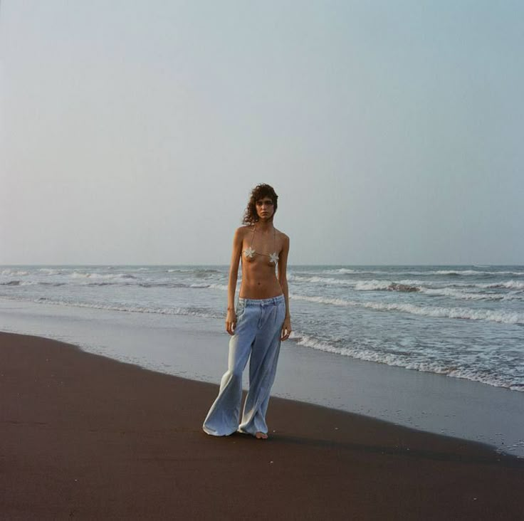 a woman standing on top of a beach next to the ocean