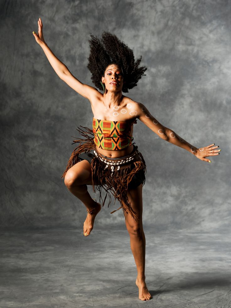 a woman is dancing with her hair in the air while wearing a native style outfit