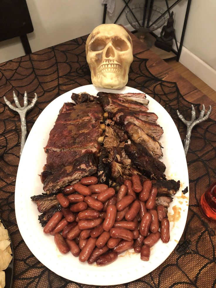 there is a plate with meat and beans on it next to a human skull head