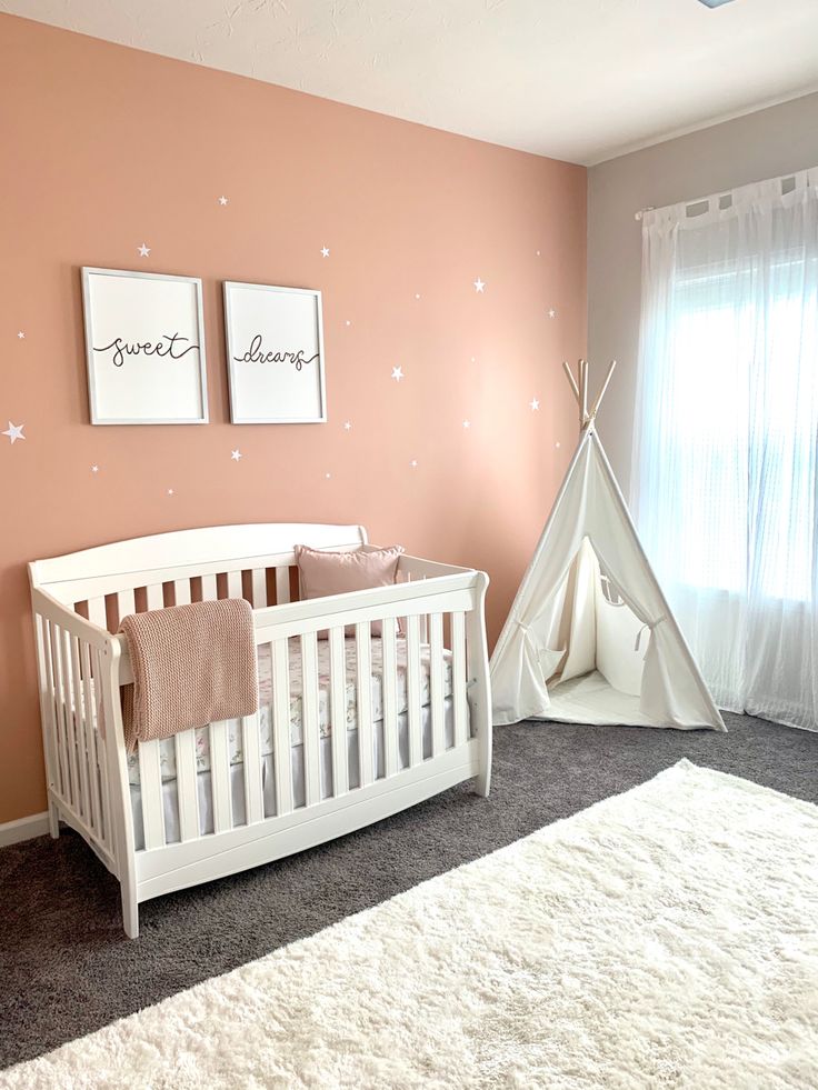 a baby's room with a teepee tent and two pictures on the wall