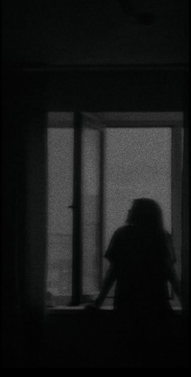 the silhouette of a person standing in front of a window