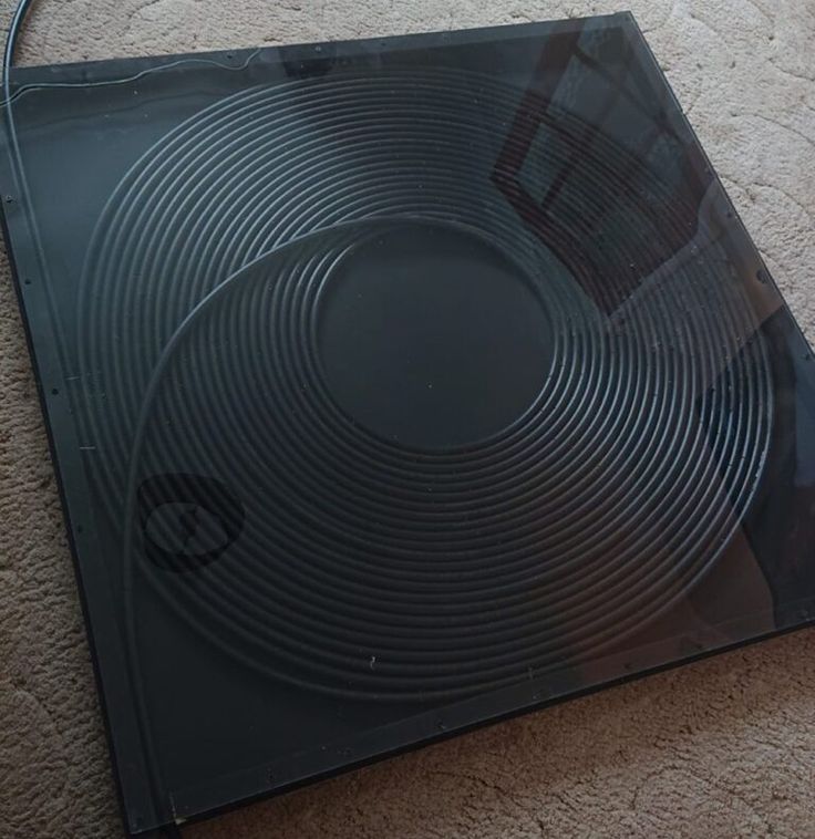 a black square shaped object on the floor with a cord attached to it's side