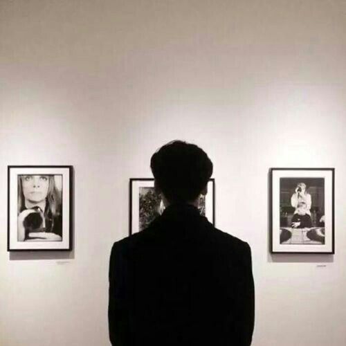 a person standing in front of pictures on the wall with their back to the camera