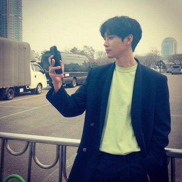 a young man taking a selfie with his cell phone in front of a parking lot