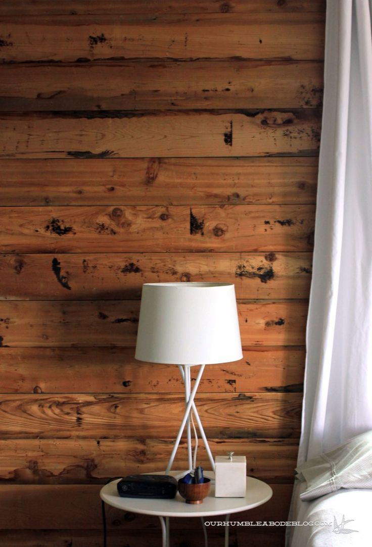 a white table with a lamp on it in front of a wood paneled wall