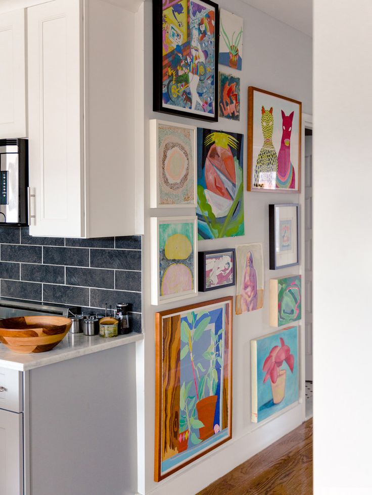 a kitchen with white cabinets and pictures on the wall