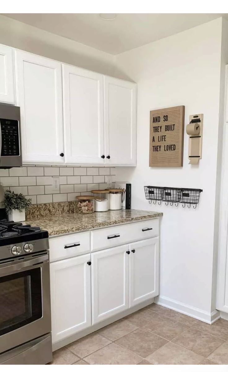 a kitchen with white cabinets, stainless steel appliances and a sign on the wall above the stove