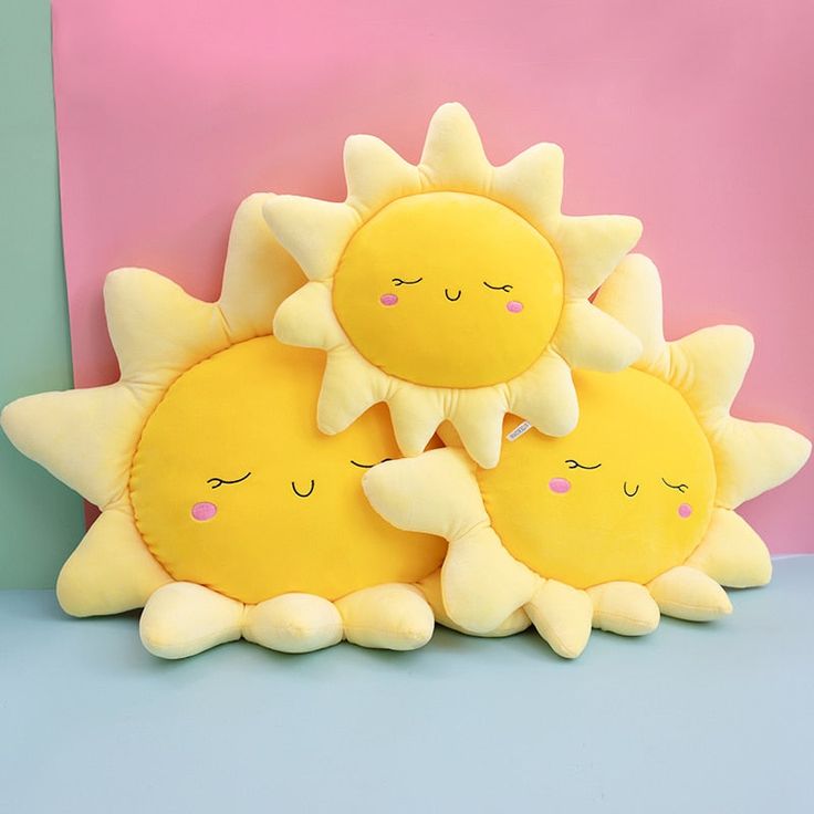 three stuffed sunflowers sitting next to each other in front of a pink and blue background